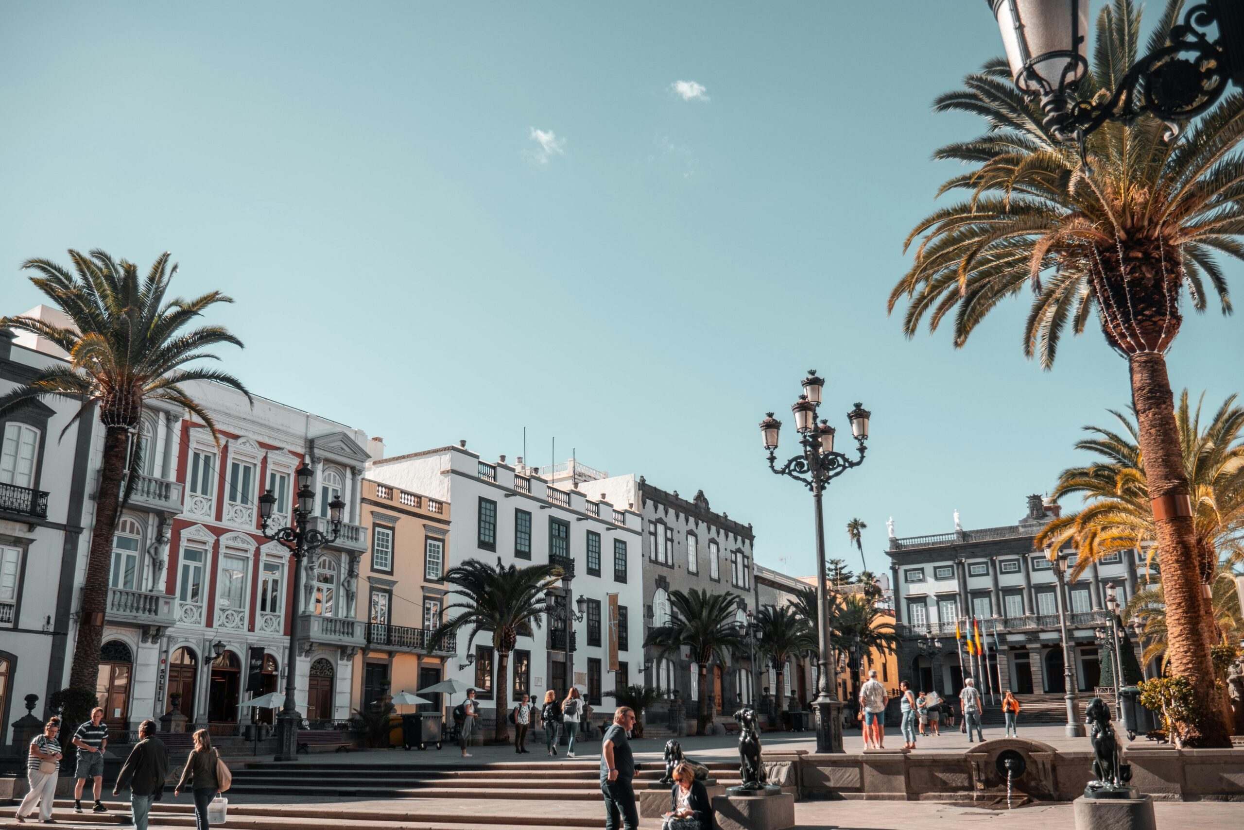A vibrant day in a city square with people and palm trees in Canary Islands, Spain.