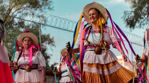 Vibrant display of Mexican heritage with women in colorful traditional costumes at a festival.