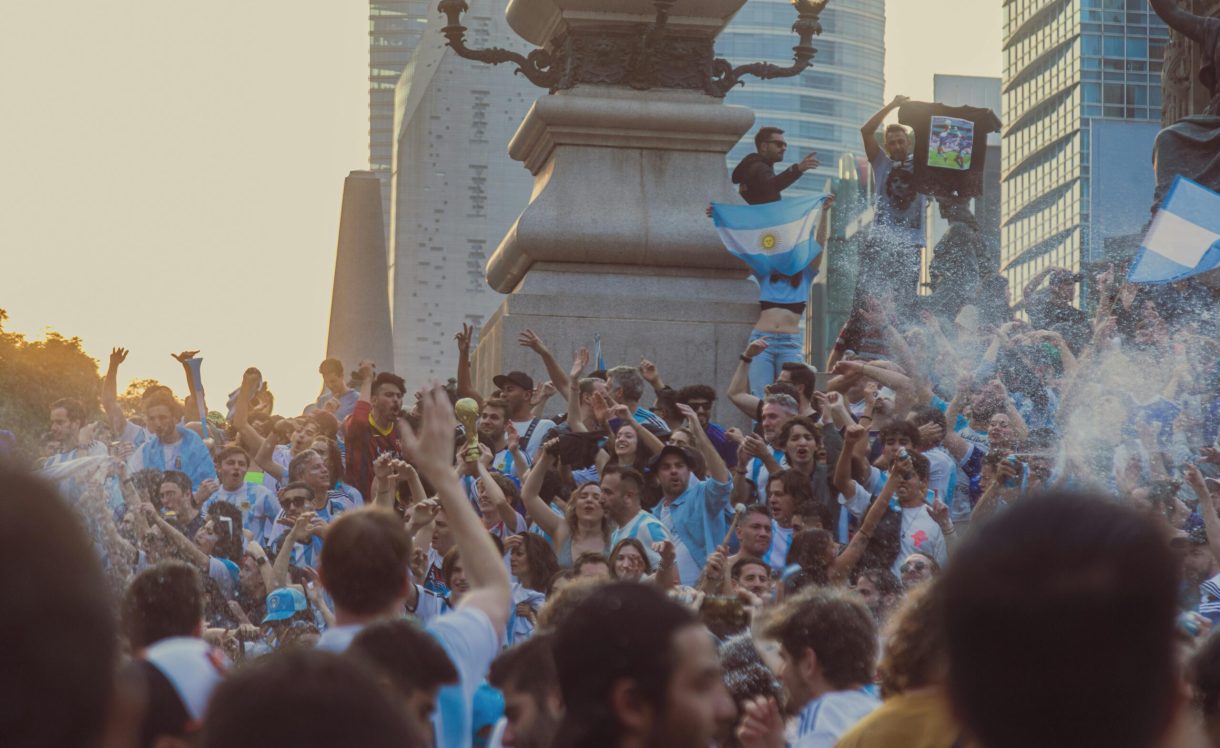 Joyful crowd celebrating soccer victory with flags in Mexico City streets.